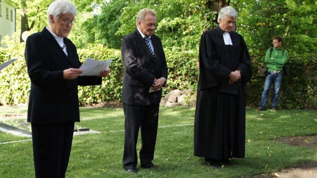 Heidemarie Grabow (Älteste im Gemeindekirchenrat), Bürgermeister Jürgen Henze und Pfarrer Matthias Scheufele an der Kriegsgräberstätte
